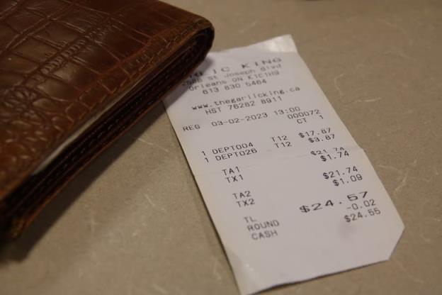 A greasy receipt is shown on a table next to a wallet.